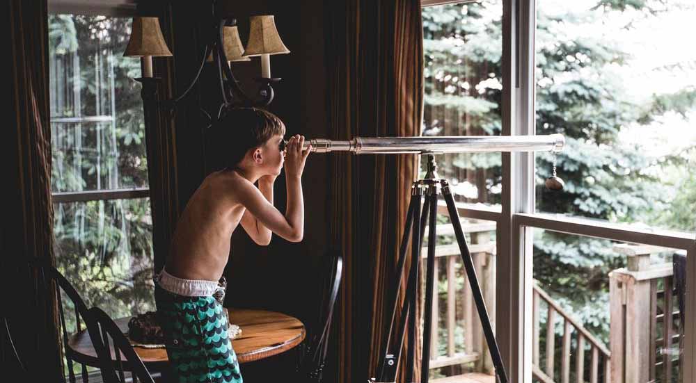 Photo of a curious kid looking through a telescope